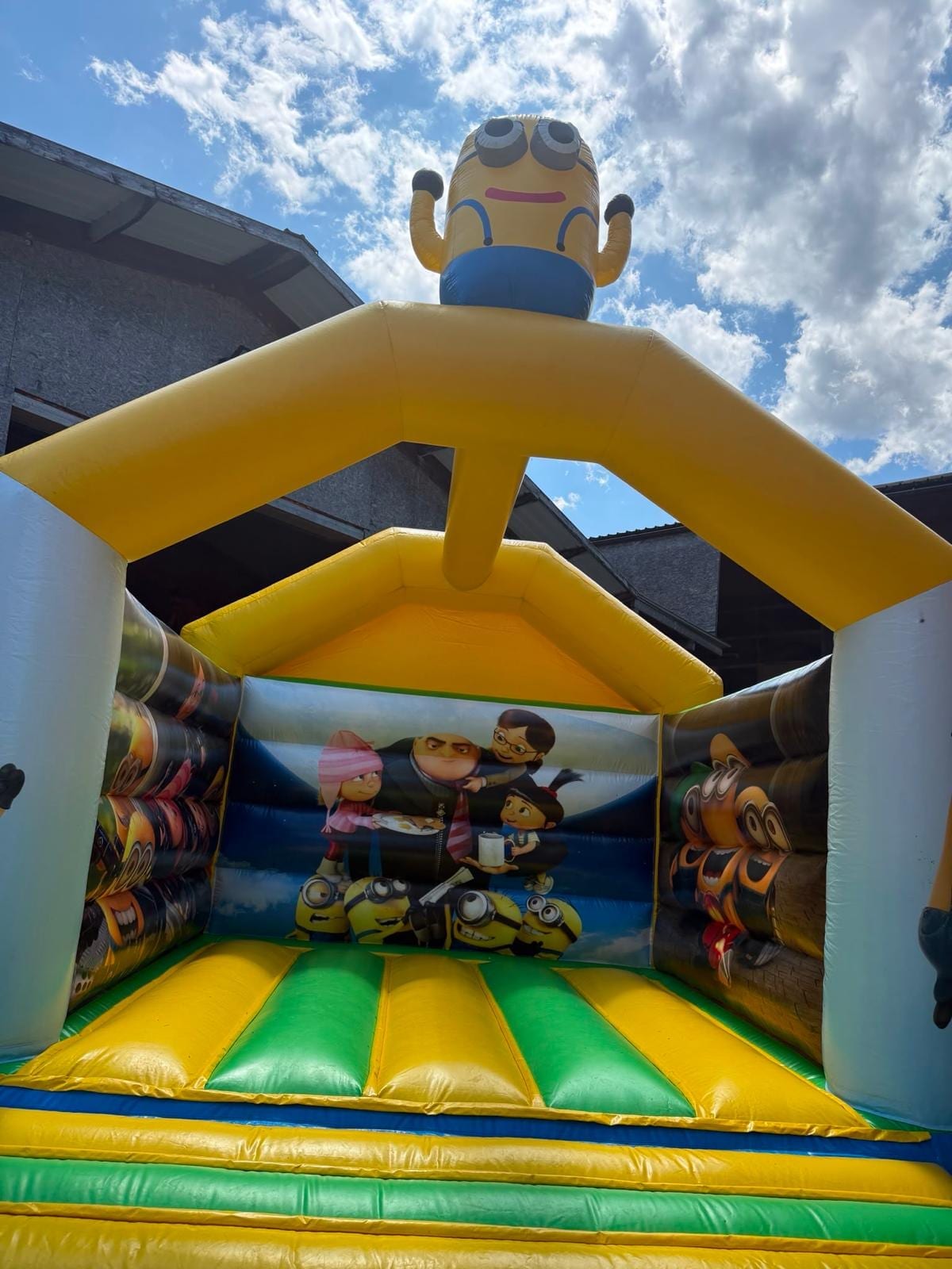 Château gonflable Minions vu en contre-plongée, tapis de saut jaune et vert